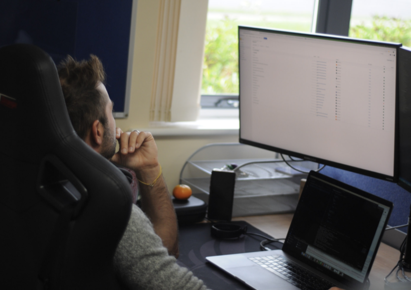 Bespoke software developer working at his desk with multiple computer windows open